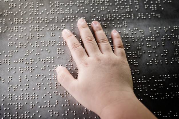 mano-nino-ciego-tocando-letras-braille-placa-metal
